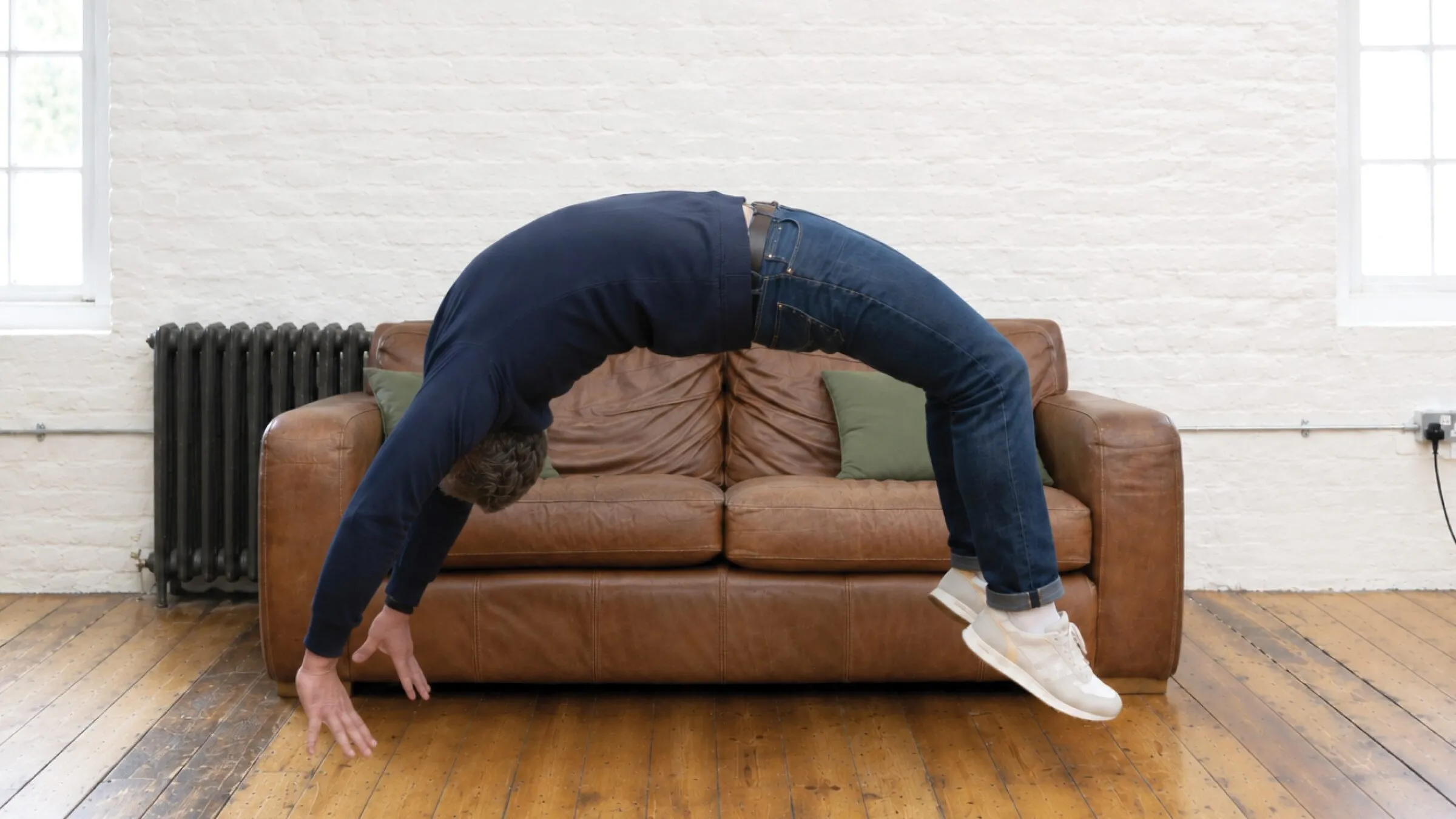A Curation team member taking a breather, bent forward over a leather sofa in the studio