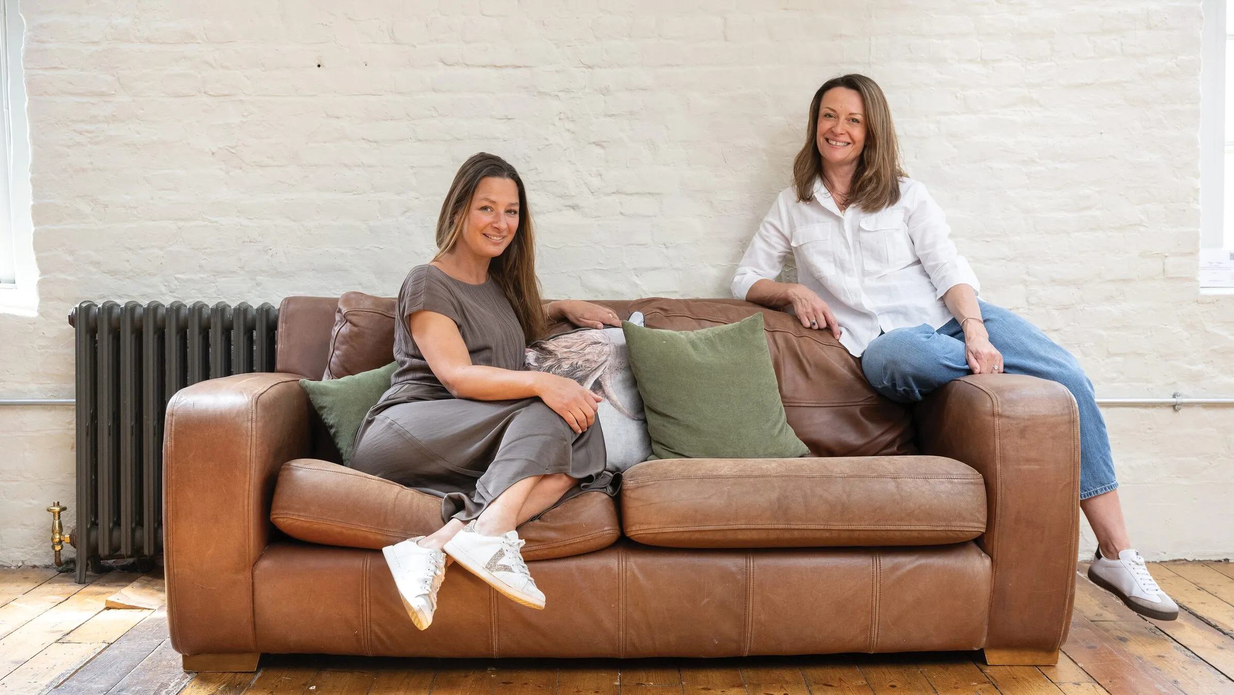 Two members of the Curation team sitting on a leather sofa