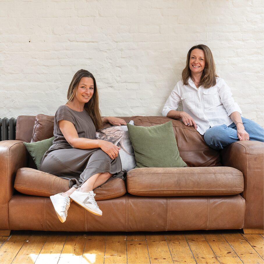 Two members of the Curation team sitting on a leather sofa